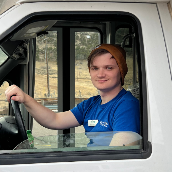 Photo of Luke Layton in the driver's seat of a parked tour bus at Dino Ridge
