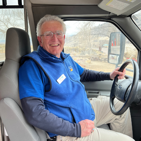 Photo of Don Cadwallader in the driver's seat of a tour bus.
