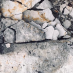 Photo of cracked fossil trace of a dinosaur footprint, damaged by erosion.