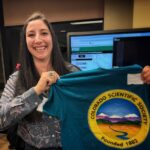 Amy Atwater holds up a Colorado Scientific Society t-shirt.