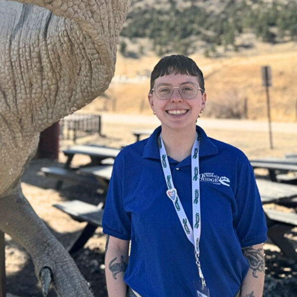 Eliza Zizka smiles next to the Iguanodon statue at the main visitor center.