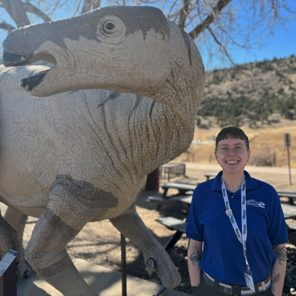 Eli Zizka smiles next to a dinosaur statue at the Main Visitor Center.