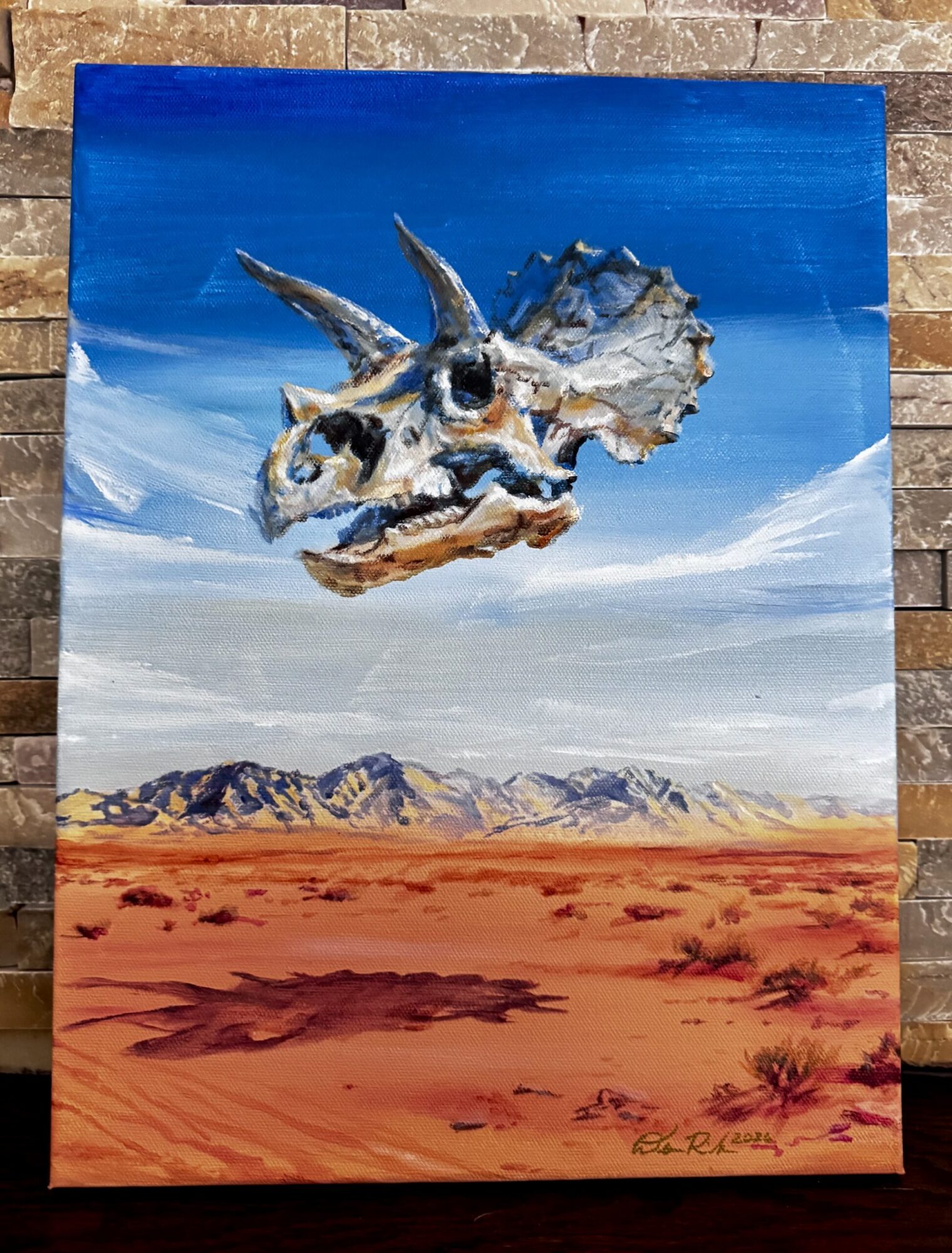 painting of a triceratops skull floating in a desert landscape.